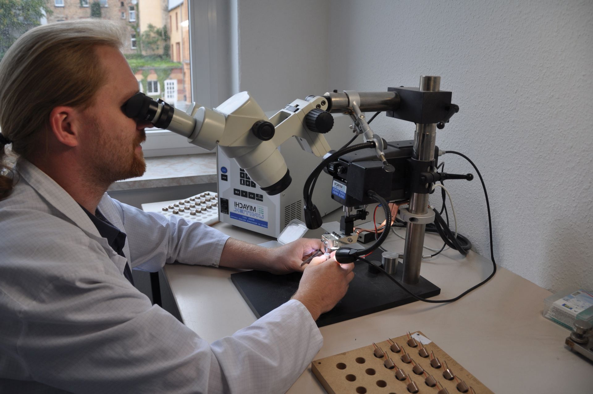 Ein Wissenschaftler sitzt an einem Stereomikroskop