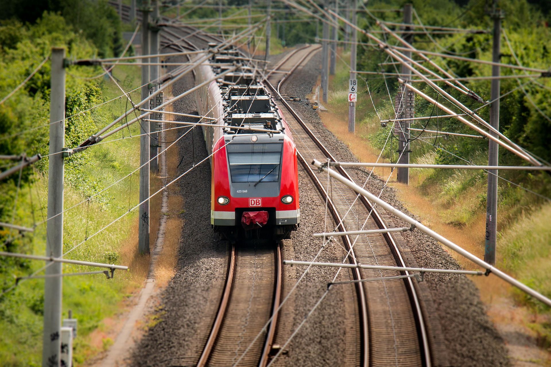 Ein Zug fährt auf einer elektrifizierten, zweigleisigen Bahnstrecke.